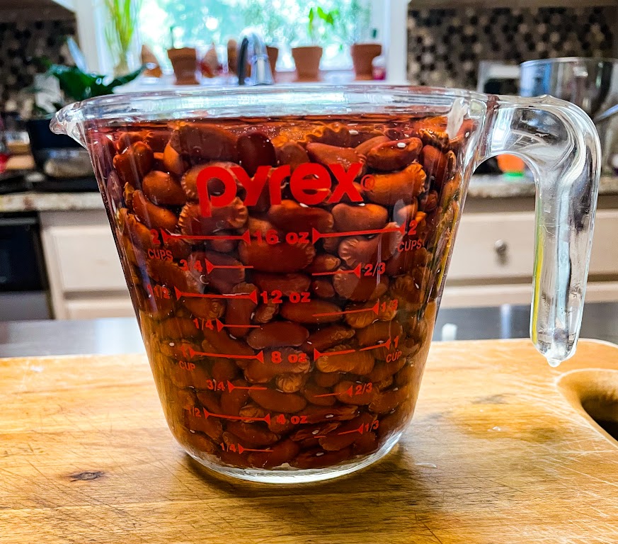 beans soaking in water inside of a  measuring cup