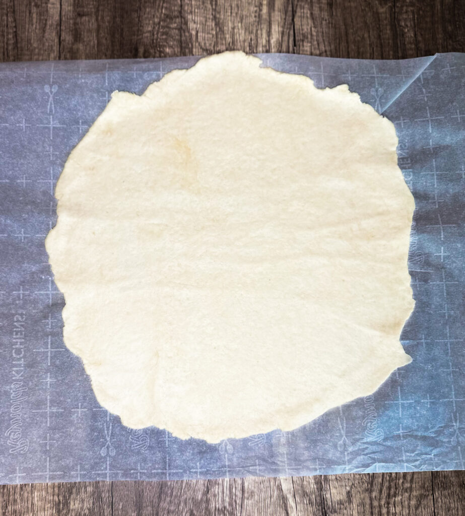 sourdough cracker dough rolled out on parchment paper