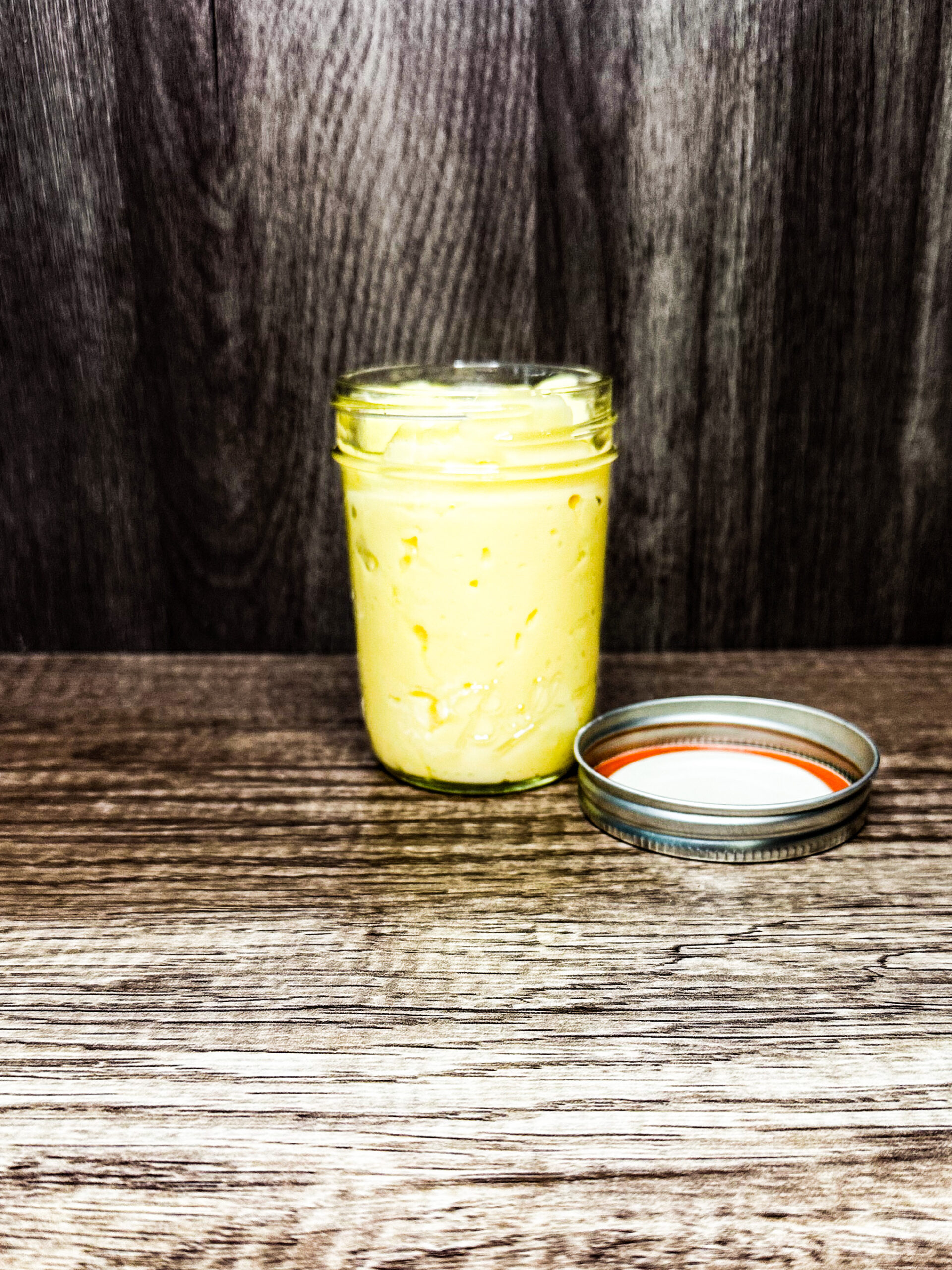 homemade mayo in a jar on a wooden counter top
