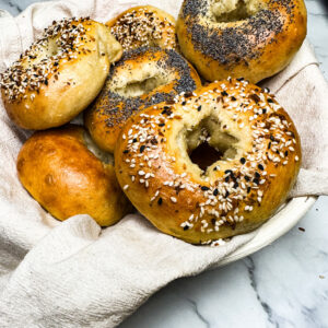 fresh baked sourdough bagels in a basket on top of a kitch counter