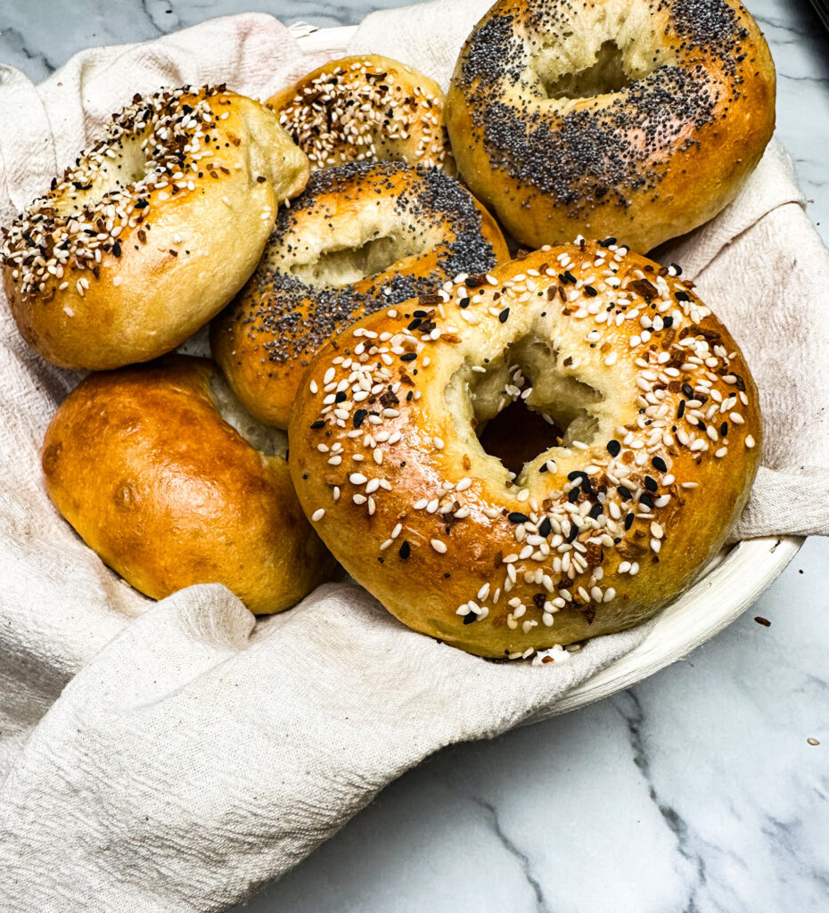 fresh baked sourdough bagels in a basket on top of a kitchen counter